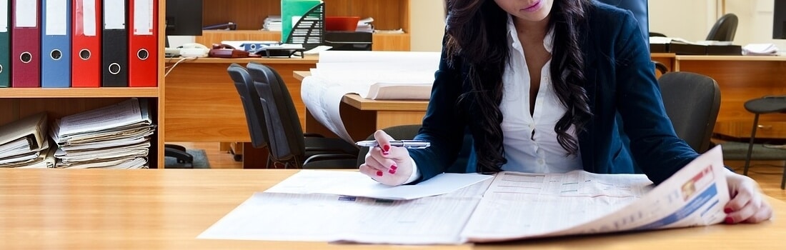 Mujer en una biblioteca lee en periódico sobre los tipos de sociedad